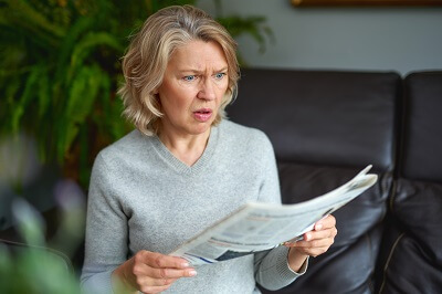 Shocked woman with newspaper